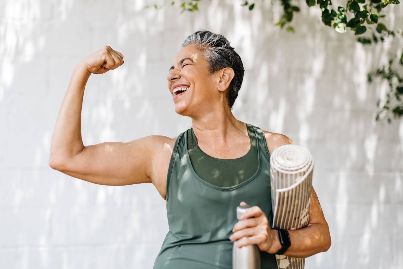 Senior woman with a short haircut, flexing her biceps outside