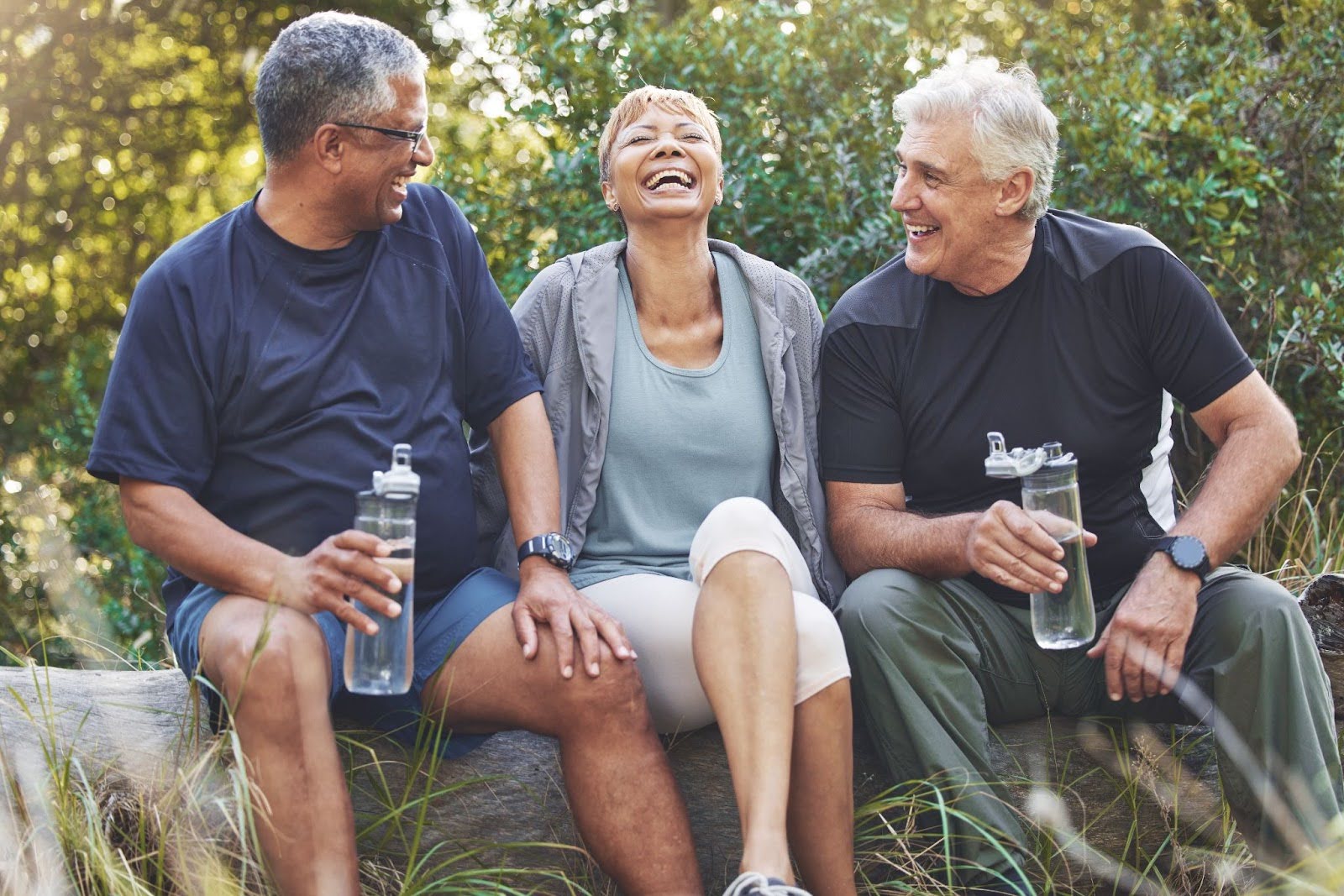 Three happy, smiling seniors drinking water outside